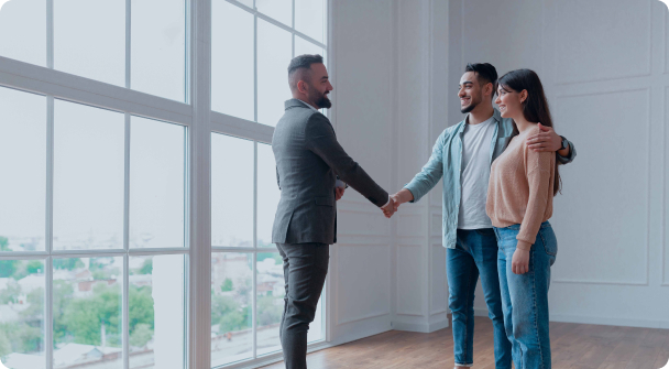 Real estate agent shaking hands with happy couple in new home
